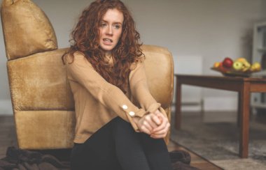 Evde dinlenen, oturma odasındaki kanepenin yanında oturan genç bir kadın. Güzel, doğal bir kız evde kalır. Görüntü tonlanır.