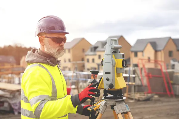 stock image Surveyor builder site engineer with theodolite total station at construction site outdoors during surveying work