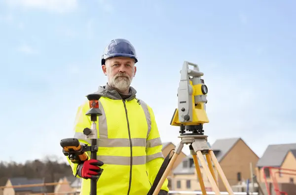 stock image Surveyor builder site engineer with theodolite total station at construction site outdoors during surveying work