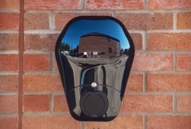 Private electric vehicle charging station fitted to the face of a red brick wall