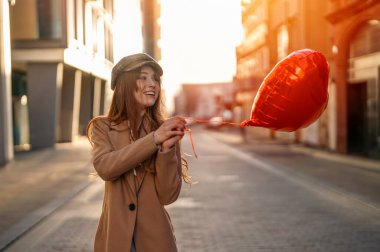 Kalp şeklinde balonu olan genç, mutlu bir kadın aşık oluyor, eğlenceli bir gün geçiriyor, İngiliz şehrinde yürüyor bahar havada yaşam tarzı, turizm, sevgililer günü, dünya kadınlarının günü konsepti