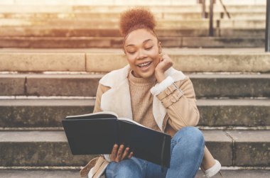 Güzel, Afro-Amerikan bir kız öğrencinin portresi şehrin basamaklarında oturmuş ders çalışma planları yapıyor.