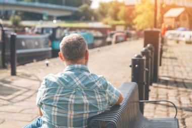 Sonbaharın son ılık günlerinde rıhtımda oturan olgun bir adamın sırtında.