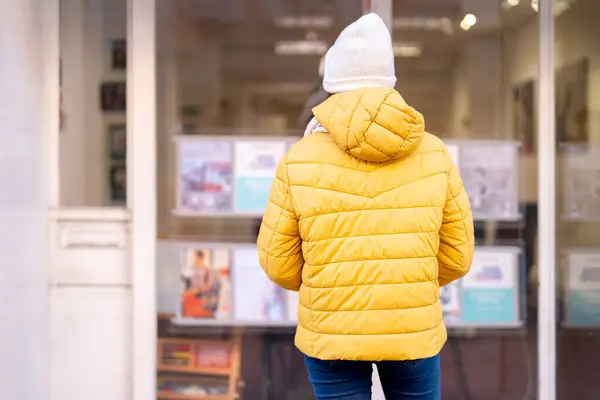 stock image young first time buyer in front of estate agency looking at advertised properties, trying to find affordable house to buy or rent