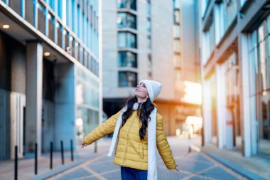 Gülümseyen genç bir kadın, şehir merkezinde cep telefonlarını kullanarak eğleniyor. insanlar, iletişim, alışveriş ve yaşam tarzı kavramı