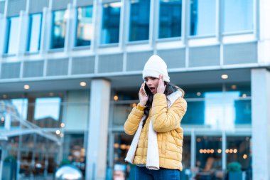 Kötü haberi olan genç bir kadın, şehir dışında bir kış şehrinde cep telefonu kullanıyor. insanlar, iletişim, alışveriş ve yaşam tarzı kavramı