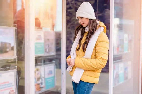 stock image young first time buyer in front of estate agency looking at advertised properties, trying to find affordable house to buy or rent