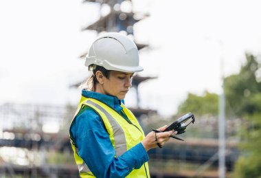 Bir inşaat şantiyesinde Theodolite toplam istasyon EDM ekipmanıyla çalışan kadın inşaat mühendisi araştırmacısı.