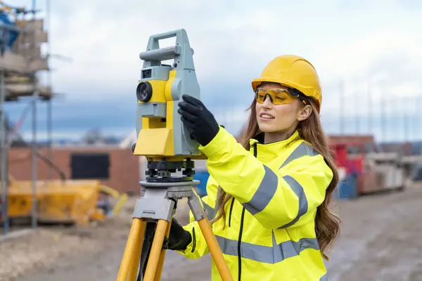 stock image Female site engineer surveyor working with theodolite total station EDM equipment on a building construction site outdoors