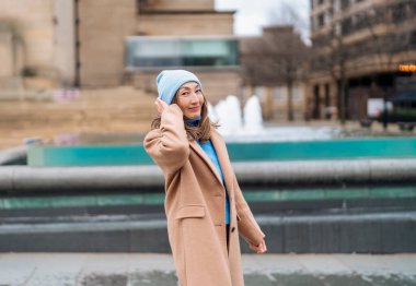 Gülümseyen mutlu Asyalı kadın, eğleniyor ve bahar günü şehirde dolaşıyor.