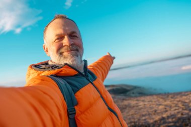 Mutlu, olgun bir adam, soğuk, güneşli bir kış gününde dağların tepesinde bulutlara karşı oturarak hayatın tadını çıkarıyor. Seyahat yaşam tarzı konsepti