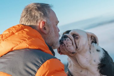 Yaşlı olgun bir adam köpeğiyle dağlarda yürüyüş yapıyor, sağlık için egzersiz ve uygunluk, sağlıklı yaşam tarzı ve gülümseme. Bir kayanın üzerinde oturan, sakin bir gün geçiren yaşlı ve olgun bir beyefendinin yüzü.