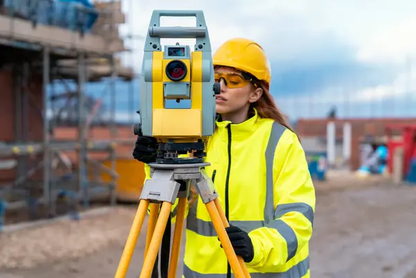 Bir inşaat şantiyesinde Theodolite toplam istasyon EDM ekipmanıyla çalışan kadın inşaat mühendisi araştırmacısı.