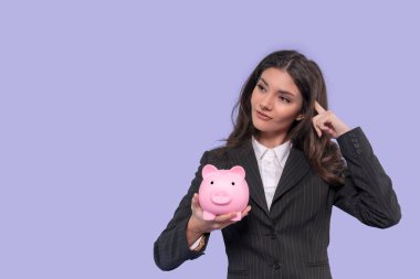 Akıllı ceketli mutsuz bir kadın birikim, yatırım, tasarruf, para, depozito olmadan boş domuz kumbarası keşfediyor. Mor arka planda fotokopi alanı ile izole edilmiş kapalı stüdyo görüntüleri