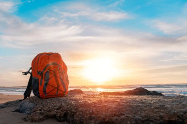 Deniz kenarındaki turuncu sırt çantası harika bir havada denize karşı. Seyahat sigortası konsepti. Hafif seyahat et.