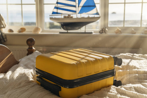 Чемодан или сумка для багажа в классическом старом номере отеля с видом на море под лучами солнца