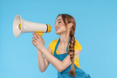 Kadın mavi arka planda megafona bağırıyor.