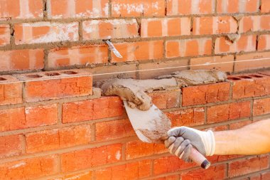 İnşaat alanına tuğla döşeyen tuğla ustasından eldivenlerle el ele tutuşan Masonry Trowel.