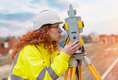 Theodolite EDM ekipmanlarıyla birlikte inşaat alanında çalışan kadın inşaat mühendisi.