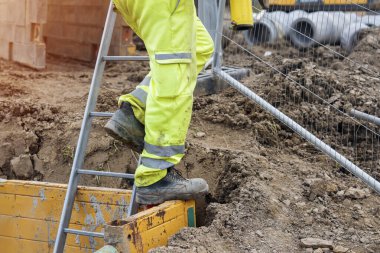 İnşaatçı güvenli siper kutusundan çıkmak için merdiven kullanıyor.