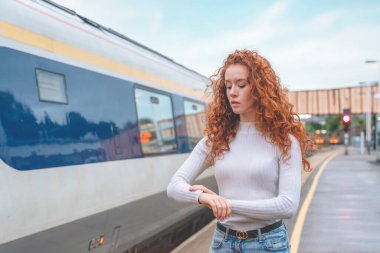 Endişeli gezgin kadın tren istasyonunda tren bekliyor seyahat konsepti