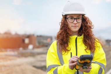 Güler yüzlü çıraklık dönemi kadın inşaat mühendisi dayanıklı tablet inşaatında çalışıyor.