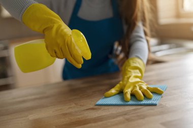 Eldivenli kadın elleri ve mutfak önlüğü temizleme masası.