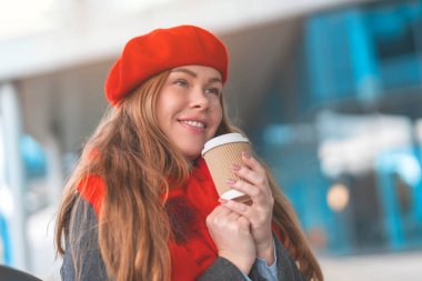 Mutlu genç bir kadın kahve içerken şehir hayatı konseptinde oturuyor.