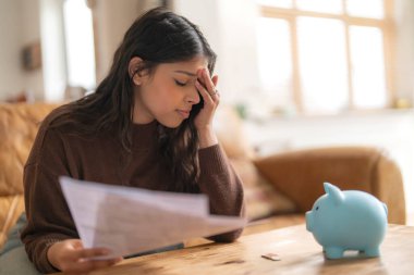 Hayal kırıklığına uğramış genç Hintli kadın mektup okuyor tasarruf vergisi ödüyor enerji faturasını ödüyor.