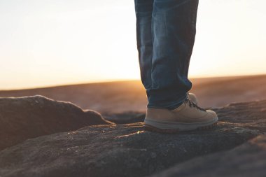 Gün doğumunda ya da günbatımında dağların zirvesine ulaşan botlu bir adam. Seyahat yaşam tarzı konsepti