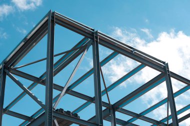 Steel frame  building under construction against blue sky clipart