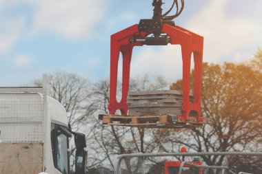 Construction materials delivered on site and being offloaded by hydraulic truck mounted crane clipart