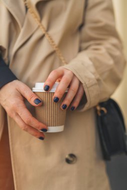 Elinde kağıt bardakta kahve tutan bir kadının elleri.