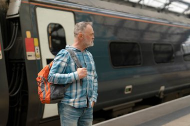 Tren istasyonunda tren bekleyen bir adam var..