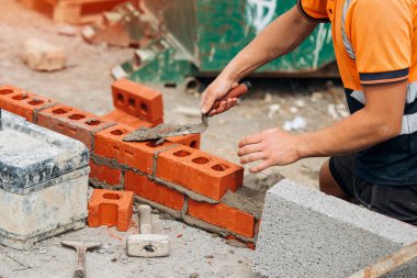 İnşaat işçisi tuğla döşeyen tuğlalar döşeyen mala ve havan topuyla