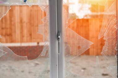 Kırık camlı ve beyaz çerçeveli kırık bir pencere var.
