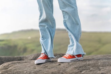 Mavi Kot ve Kırmızı Spor Ayakkabıları Giyen Kaya Üzerinde Duran Kişi