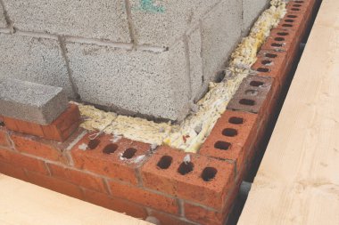 Köpük yalıtımı ve odun kalası olan tuğla duvar köşesi.