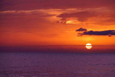 Denizde gün doğumu. Su yüzeyinde yanan gökyüzü. Güneş ufuktan yükseliyor. Sabah deniz manzarası.
