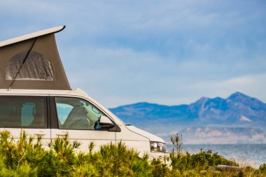 Akdeniz kıyısında çatıda çadırı olan bir minibüs. Tatillerde ve seyyar evlerde. Vanlife.