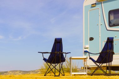 Camp equipment chairs and table at caravan. Wild camping on nature. Holidays and traveling in motor home.