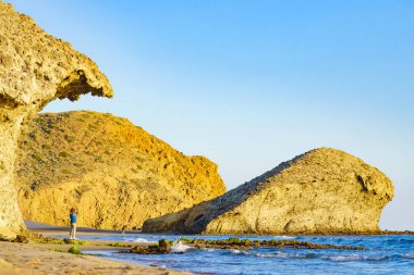 Cabo de Gata Nijar Doğal Parkı 'ndaki Monsul sahilinde yürüyen insanlar. Almerya kıyıları. Turist çekmek için büyük lav oluşumu.