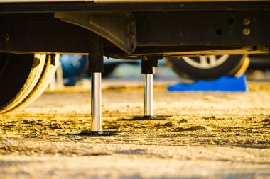 Kamp için otomatik seviye sistemi. Hidrolik sabit bacak kullanımda. Arkadaki karavan için mavi rampa tıkanıklığı.