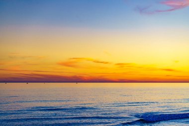 Deniz yüzeyinde gün batımında renkli gökyüzü.