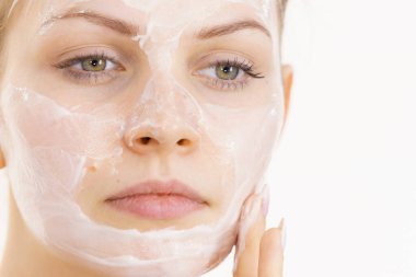 Genç bir kadın krem kozmetik uyguluyor, yüzüne nemlendirici maske takıyor. Güzellik tedavisi. Cilt bakımı.