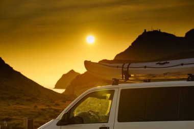 Gün batımında çatıda kanosu olan bir araba, dağ doğasına karşı. Cabo de Gata Nijar Doğal Parkı, Almerya ili, Endülüs İspanya. Etkin yaşam biçimi.