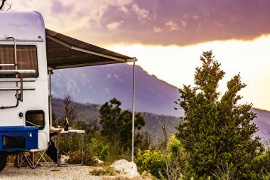 Kapalı tenteli bir kamp aracı ve Fransız dağlarında sandalyeli bir turist masası. Doğada kamp yapmak. Tatiller ve karavanla seyahat.