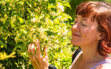 Beyaz çiçek kokan bir kadın. Olgun bir kadın doğanın tadını çıkarıyor.