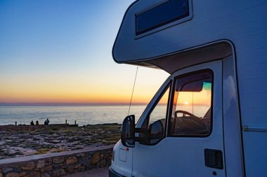 İspanya 'nın Akdeniz kıyısında gün batımında kamp aracı. Doğada kamp yapmak. Tatil ve karavanda seyahat.
