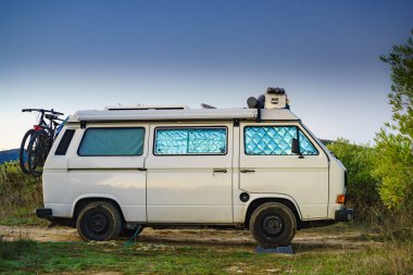 Camper van with internal thermal screen blind at window pane camping on nature in summer. Vanlife. Caravan vacation.